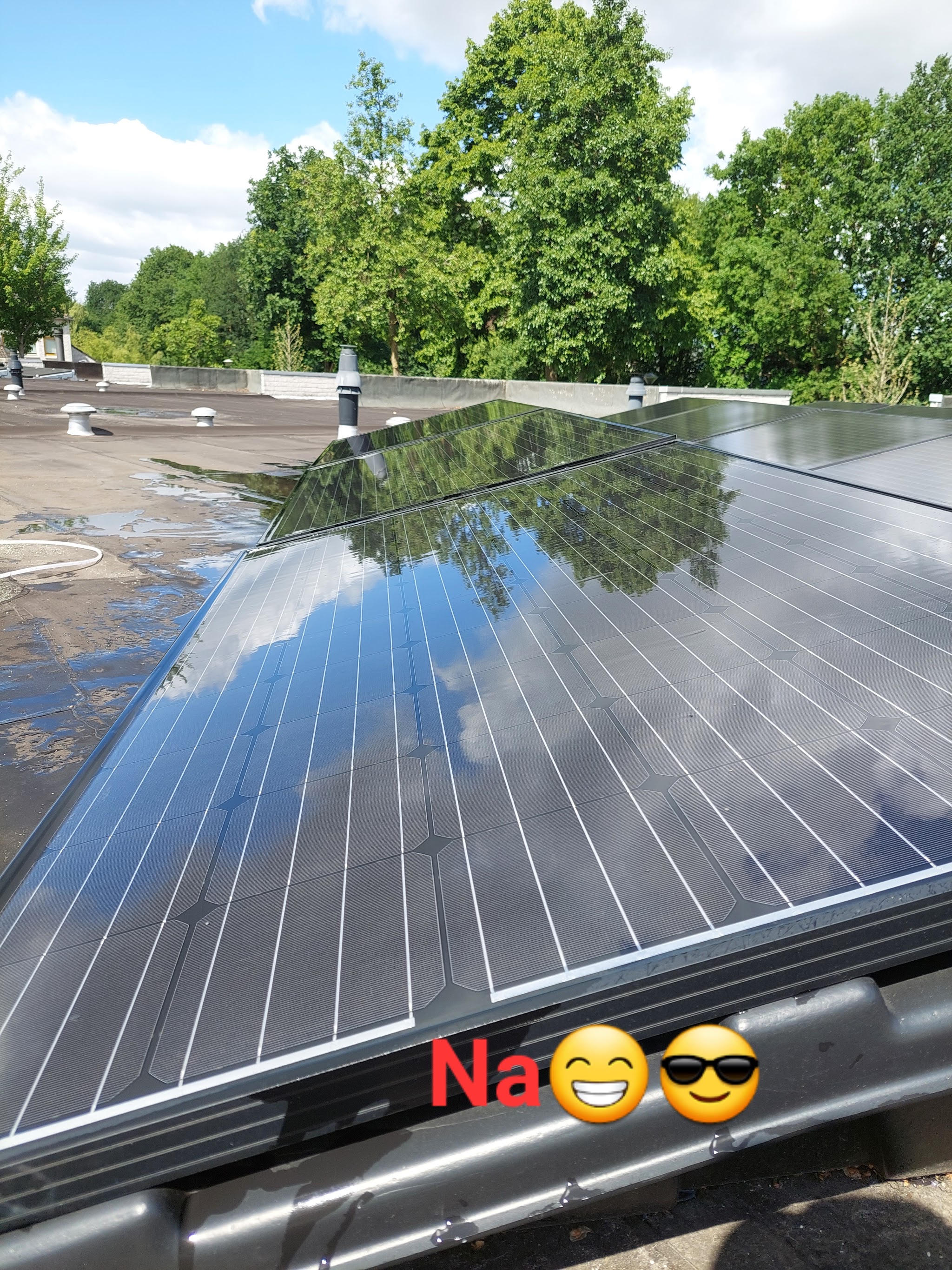 Dezelfde zonnepanelen op het platte dak, schoon na de wasbeurt